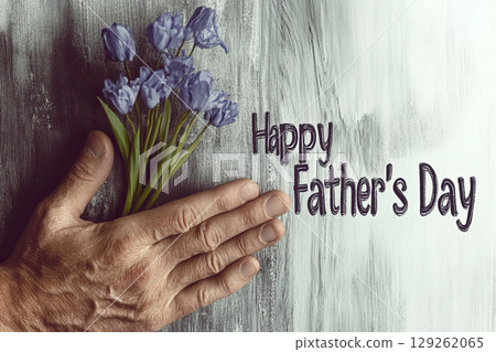 Hand holding flowers with a heartfelt message for Father's Day celebration 129262065