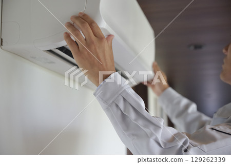 Hands of a male worker inspecting an air conditioner Hands of a male worker inspecting an air conditioner 129262339