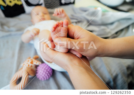 Close up Father massages baby's legs by fingers and with massage ball. Healthy massage. Massage therapist. Sensory tactile activities. Massage textured balls for kid. Earlier development. Focus picked 129262350