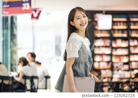 站在圖書館裡微笑的年輕女子 站在圖書館裡微笑的年輕女子 129262728