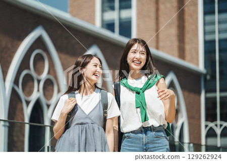 A female college student walking around the campus, chatting happily with her friends A female college student walking around the campus, chatting happily with her friends 129262924