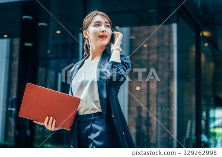 一位身穿西裝的年輕女商人在辦公室打電話 129262998