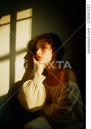 A woman is sitting in a room with a window behind her 129263317