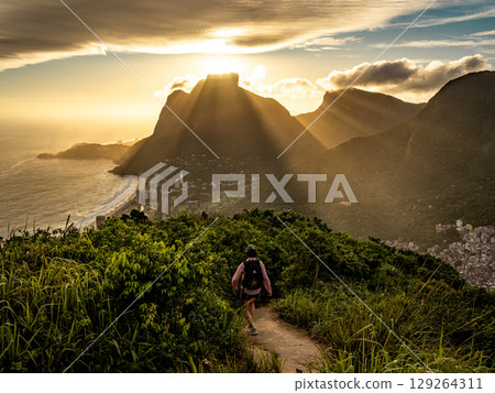 Golden Sunset Over Rio De Janeiro From Two Brothers Mountain: Dramatic Sunbeams Streaming Through Coastal Peaks Above The Atlantic Ocean And Leblon Beach Golden Sunset Over Rio De Janeiro From Two Brothers Mountain: Dramatic Sunbeams Streaming Through Coastal Peaks Above The Atlantic Ocean And Leblon Beach 129264311
