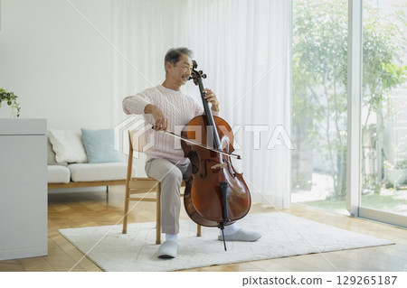 一位 60 多歲的男子在家中拉大提琴 129265187