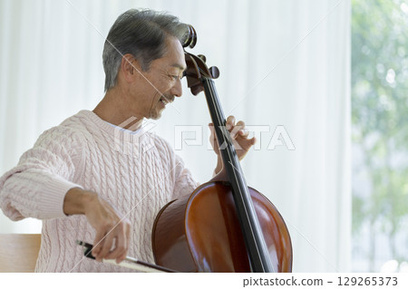 Profile of a man in his 60s playing the cello Profile of a man in his 60s playing the cello 129265373