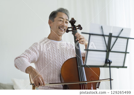 A smiling man in his 60s playing the cello A smiling man in his 60s playing the cello 129265499