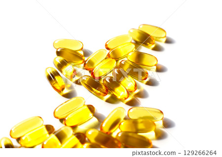 Golden fish oil capsules on white background. Golden fish oil capsules on white background. 129266264