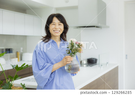 Woman holding a vase in the kitchen 129266285