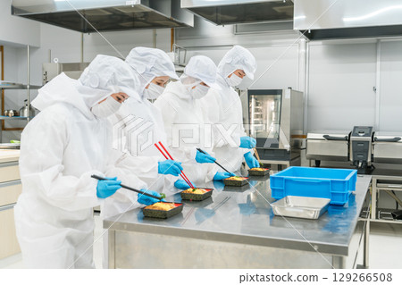 Men and women arranging lunch boxes (food factory, food processing, food hygiene) 129266508