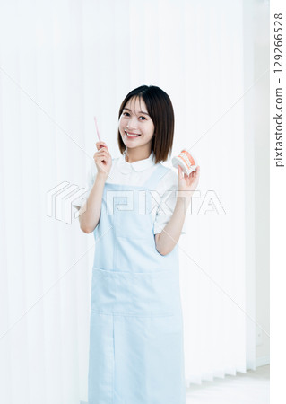 Female dental staff member giving tooth brushing instructions 129266528