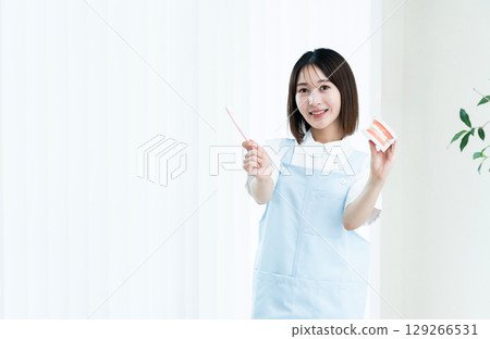 Female dental staff member giving tooth brushing instructions 129266531