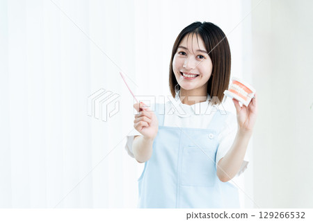 Female dental staff member giving tooth brushing instructions 129266532