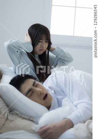 一個年輕人在床上睡覺打呼嚕 129266545