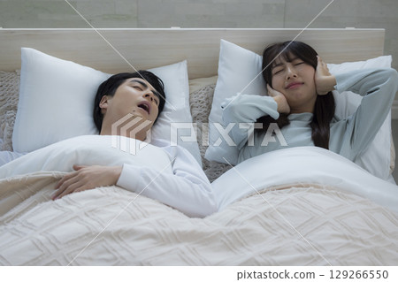 A young man sleeping and snoring in bed 129266550