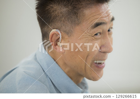 Senior man wearing a hearing aid 129266615