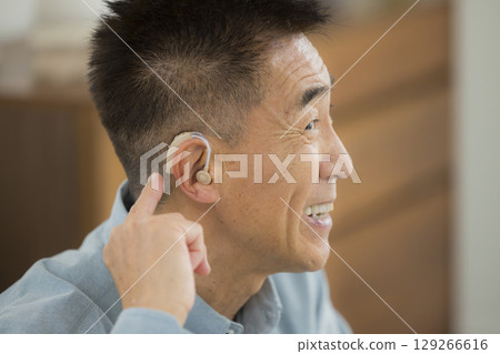 Senior man wearing a hearing aid 129266616