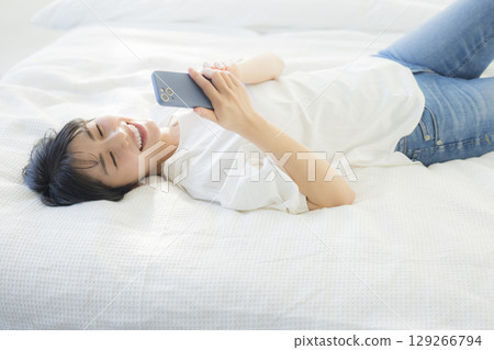 一名婦女在床上的看一個智能手機 129266794