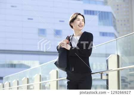 A smiling businesswoman standing in an office district 129266927