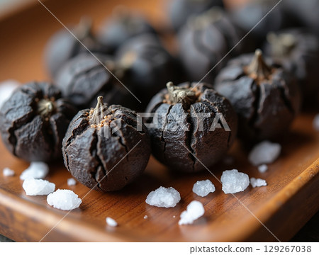 Macro Close-up of Black Peppercorns and Salt on an Aged Wooden Tray 129267038