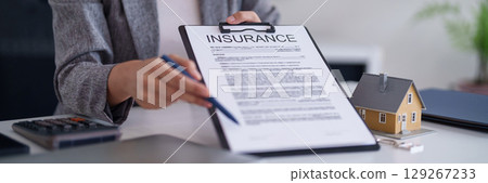 Adult Asian woman hands point to home insurance policy document on clipboard professional property advisor explains terms secures house investment future residential protection sales agent 129267233
