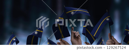 Nauru flags in their hands on a blurred urban background 129267524