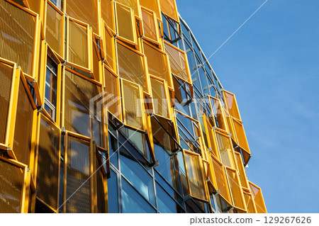 Modern Building Facade with Yellow Geometric Sunshades on Glass Windows Modern Building Facade with Yellow Geometric Sunshades on Glass Windows 129267626