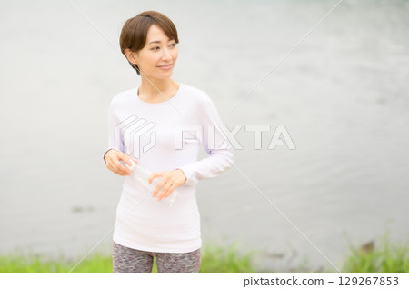A woman holding a plastic bottle to hydrate after exercise A woman holding a plastic bottle to hydrate after exercise 129267853