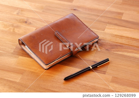 Image of doing desk work with a brown leather notebook Image of doing desk work with a brown leather notebook 129268099