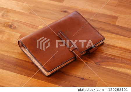 Image of doing desk work with a brown leather notebook Image of doing desk work with a brown leather notebook 129268101