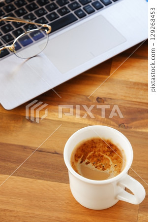Image of a man working on his laptop while drinking freshly brewed delicious coffee Image of a man working on his laptop while drinking freshly brewed delicious coffee 129268453