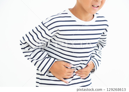 Elementary school boy holding his stomach in pain Elementary school boy holding his stomach in pain 129268613