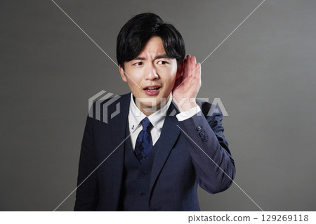 商人把手放在耳邊，黑色背景 129269118