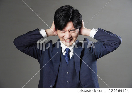 Businessman covering his ears black background 129269124