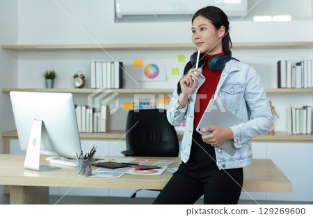Thoughtful Young Woman in Modern Office with Tablet and Headphones 129269600