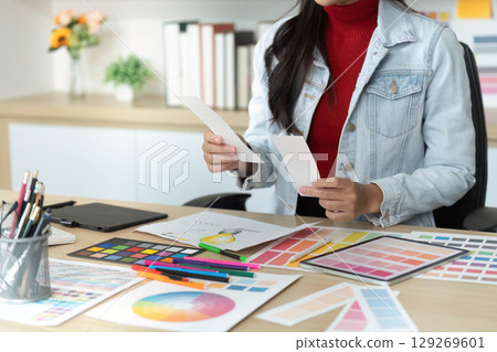 Designer Reviewing Color Samples and Sketches in Office 129269601