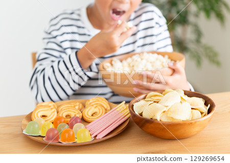 Elementary school boy eating a lot of sweets 129269654