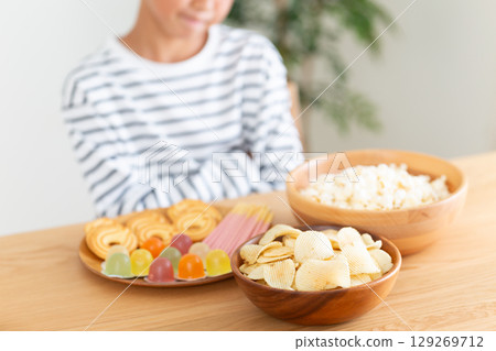 Elementary school boy refraining from eating sweets Elementary school boy refraining from eating sweets 129269712