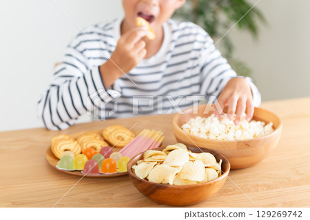 Elementary school boy eating a lot of sweets 129269742