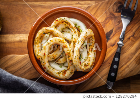 Marinated squid rings in bowl on wooden table. Top view. 129270284