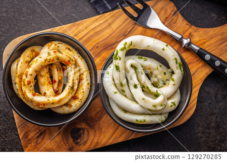 Marinated squid rings in bowl on black table. Top view. 129270285