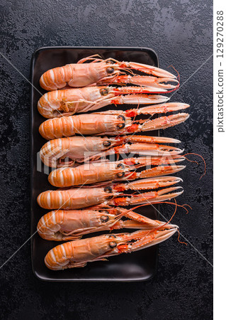 Scampi langoustine on plate on black table. Top view. 129270288