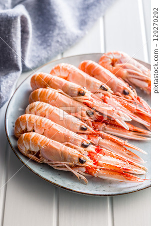Scampi langoustine on plate on white table. Scampi langoustine on plate on white table. 129270292