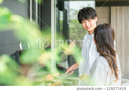 Men and women having barbecue, camping, BBQ, grilled meat, glamping (home party, balcony camping) 129271419
