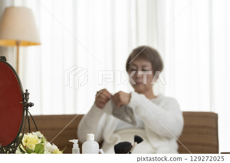 Senior woman taking care of her skin with a face mask Senior woman taking care of her skin with a face mask 129272025