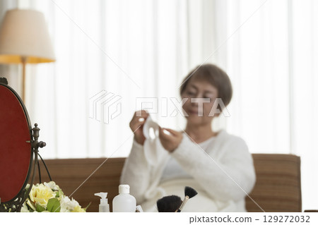 Senior woman taking care of her skin with a face mask Senior woman taking care of her skin with a face mask 129272032