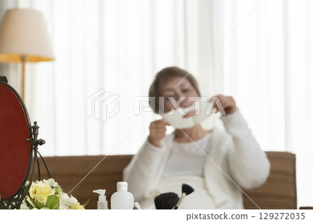 一位老年婦女戴著面膜護理皮膚 一位老年婦女戴著面膜護理皮膚 129272035