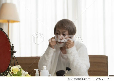 Senior woman taking care of her skin with a face mask 129272038