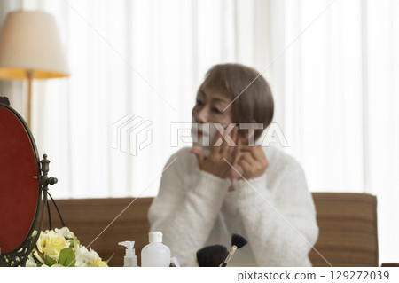 Senior woman taking care of her skin with a face mask Senior woman taking care of her skin with a face mask 129272039
