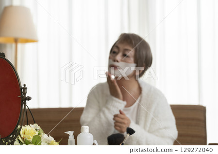 Senior woman taking care of her skin with a face mask 129272040